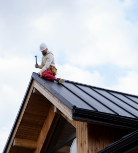 Certified roofer securing metal roof panels during residential installation
