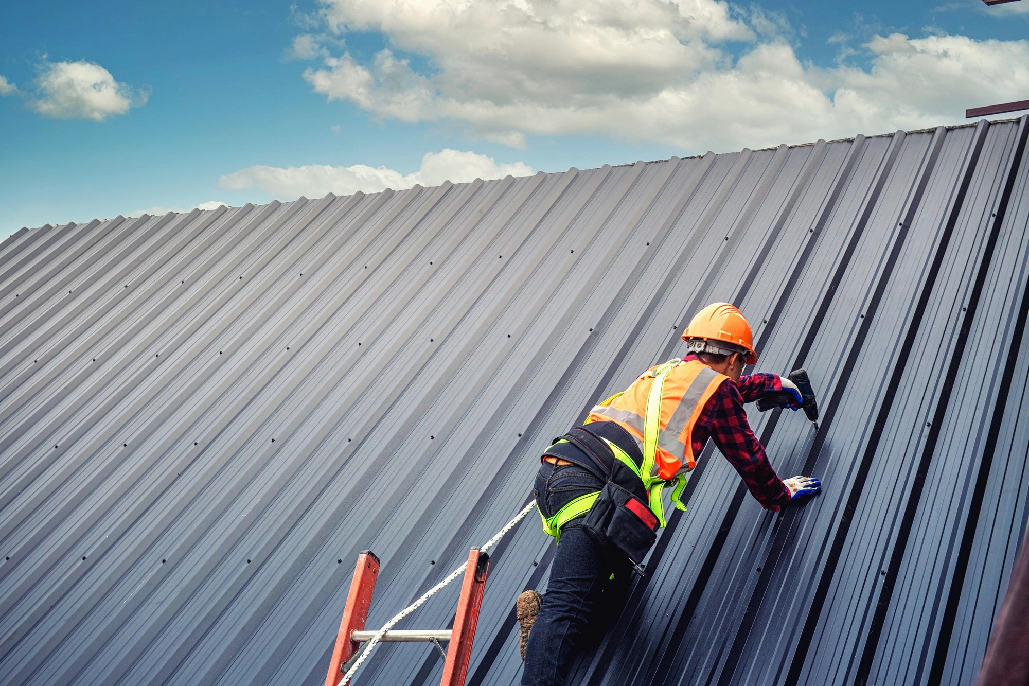 Professional metal roof installation performed with safety harness and precision tools
