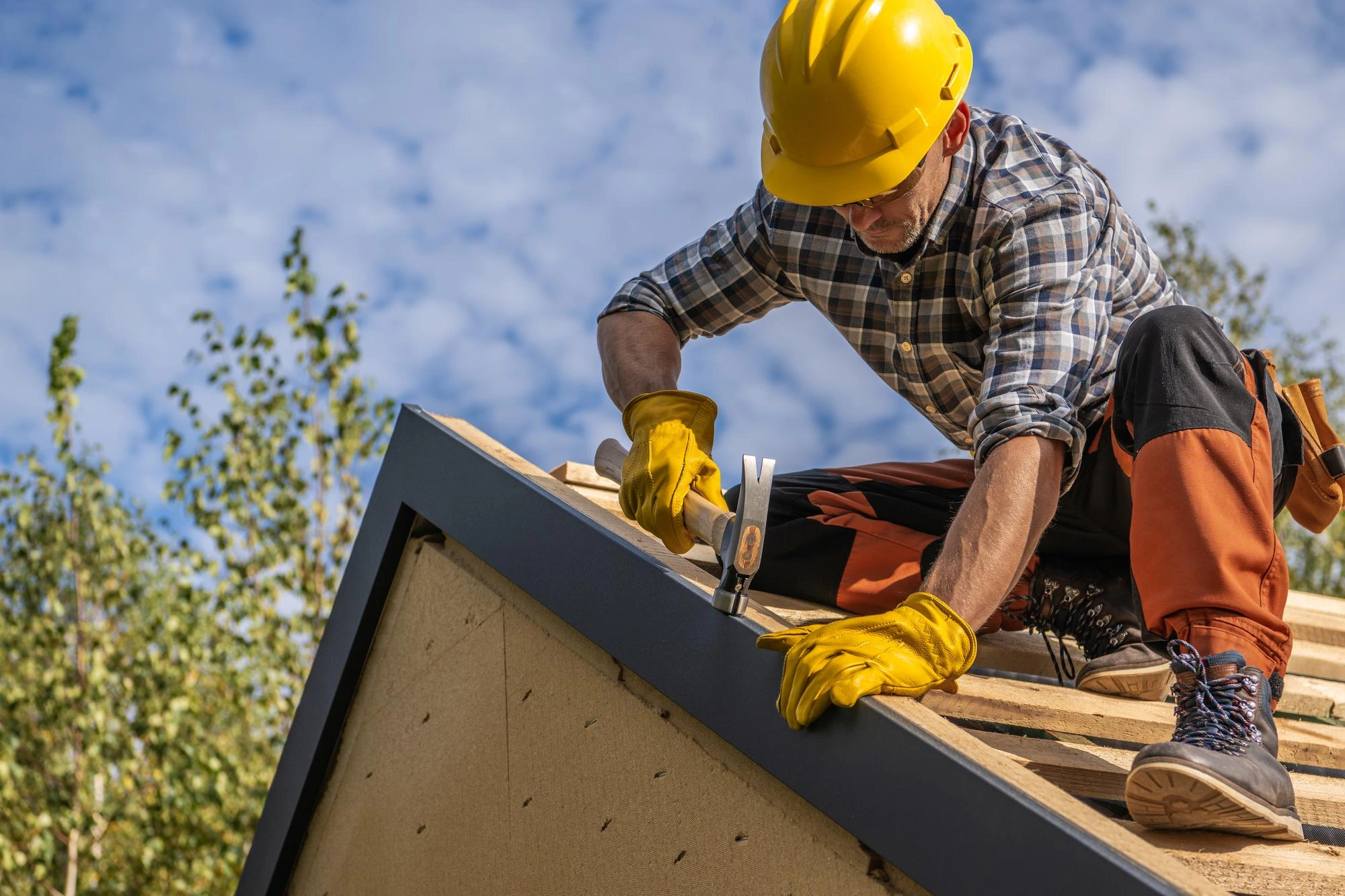 Skilled roofer repairing residential roof structure with protective safety gear